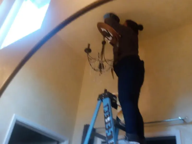Electrician installing a chandelier in a Agoura Hills residence